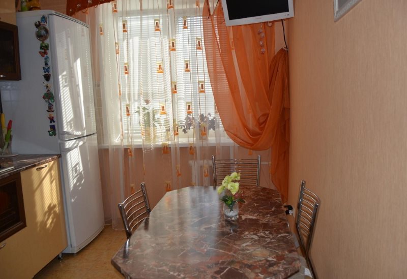 Легкая оранжевая штора на кухонном окне