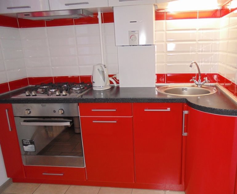 Белая газовая колонка и красный кухонный гарнитур