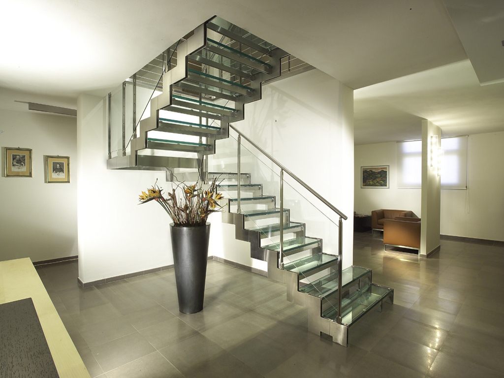 Поворотная лестница из металла и стекла в доме